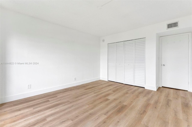 unfurnished bedroom with light hardwood / wood-style flooring and a closet