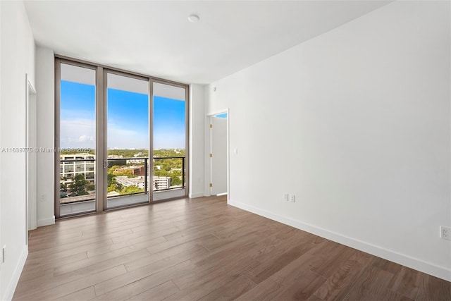 empty room with hardwood / wood-style floors and expansive windows