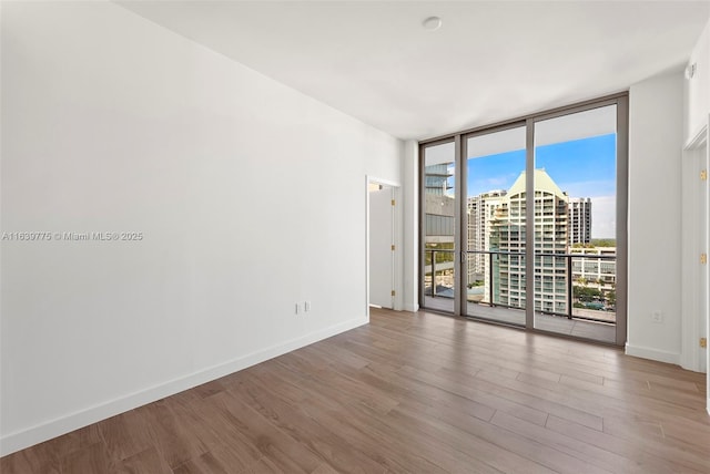 unfurnished room featuring floor to ceiling windows and hardwood / wood-style floors