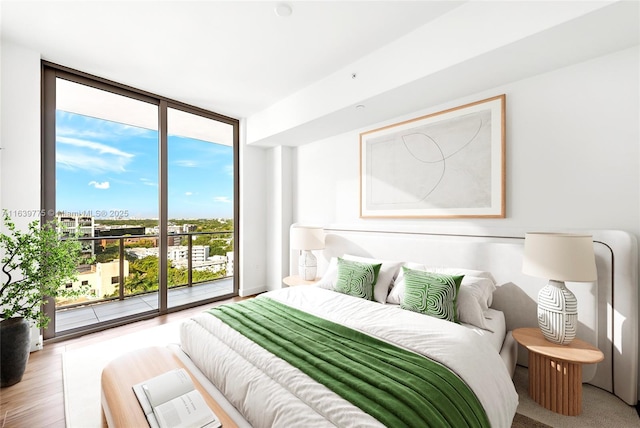 bedroom featuring access to exterior, hardwood / wood-style floors, and floor to ceiling windows