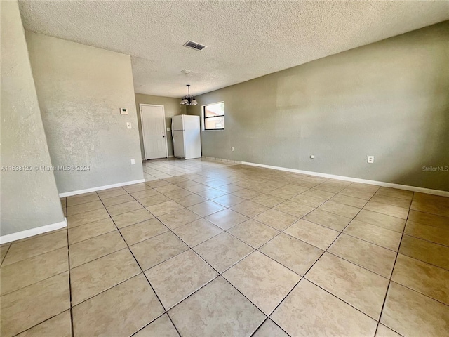 spare room with a textured ceiling and light tile patterned floors