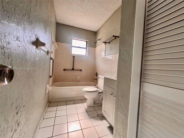 full bathroom featuring tiled shower / bath, a textured ceiling, tile patterned flooring, vanity, and toilet