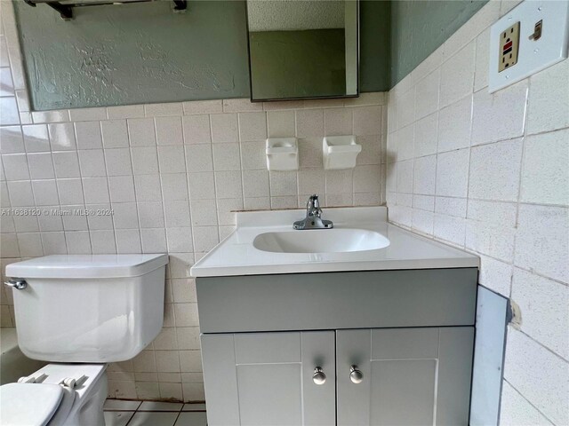 bathroom featuring tile walls, toilet, and vanity