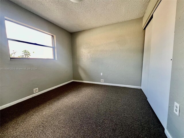 unfurnished room with carpet flooring and a textured ceiling