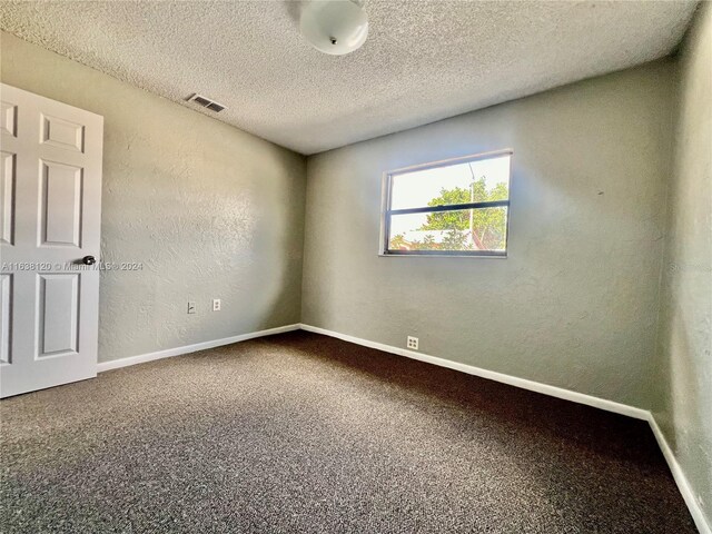 carpeted spare room featuring a textured ceiling