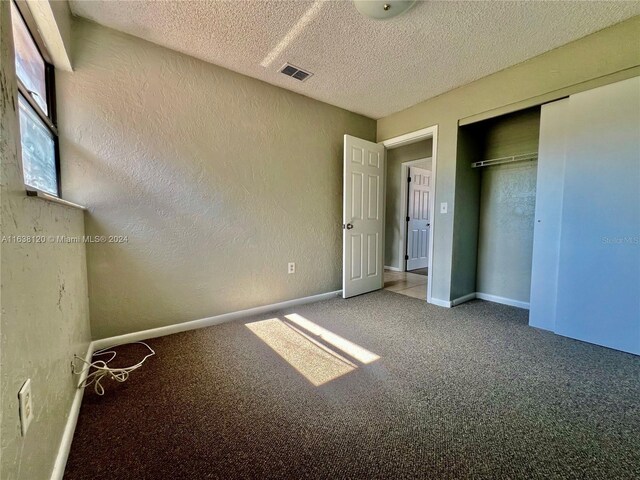 unfurnished bedroom with a closet, a textured ceiling, and carpet flooring