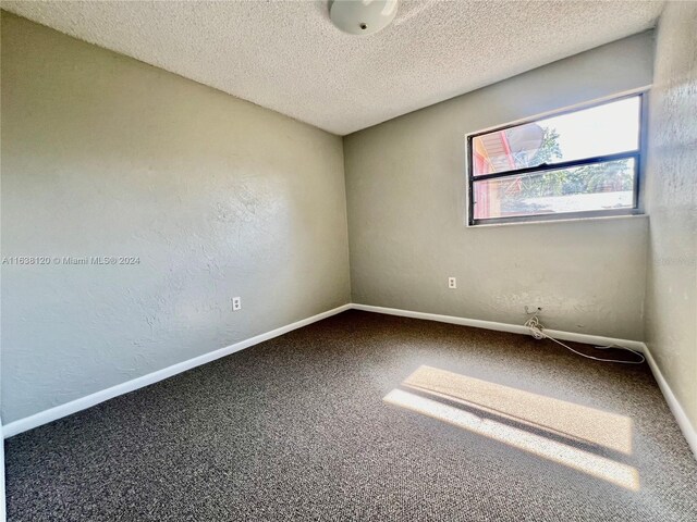 carpeted spare room featuring a textured ceiling