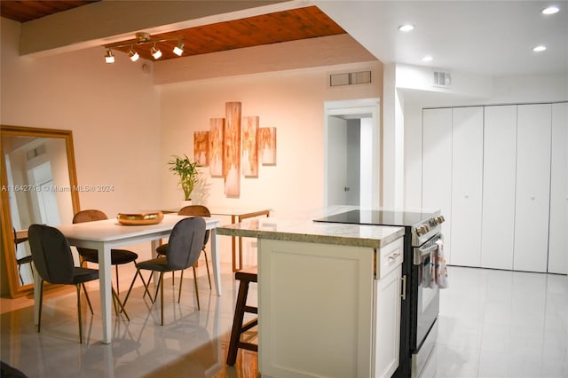 kitchen with light tile patterned flooring, light stone counters, wooden ceiling, track lighting, and electric stove