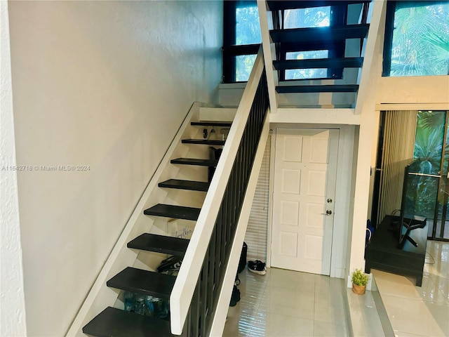 stairway featuring a towering ceiling and tile patterned flooring