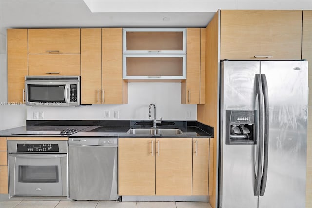 kitchen featuring dark stone counters, sink, light tile patterned floors, and stainless steel appliances