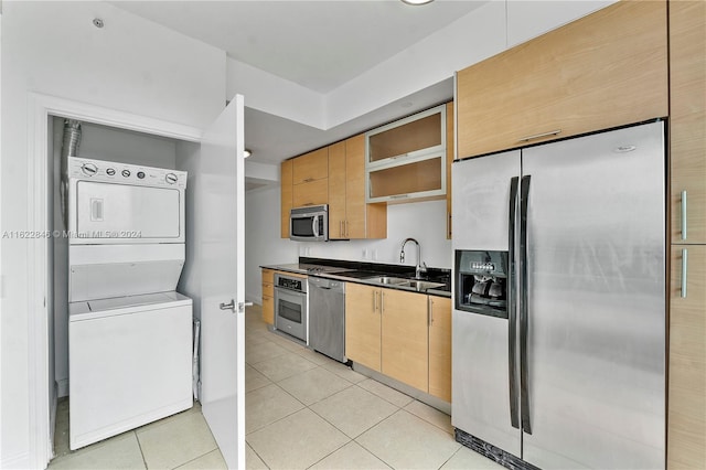 kitchen featuring stacked washer / dryer, sink, stainless steel appliances, light brown cabinets, and light tile patterned floors