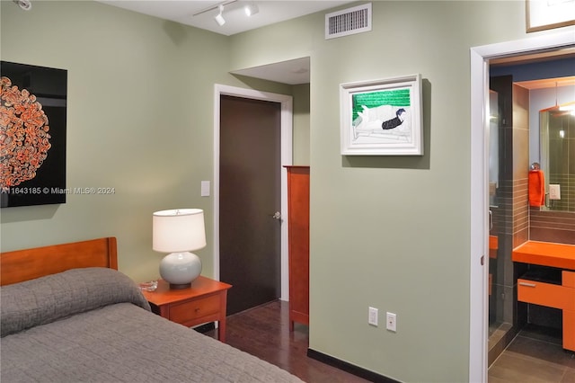 bedroom featuring rail lighting and dark wood-type flooring