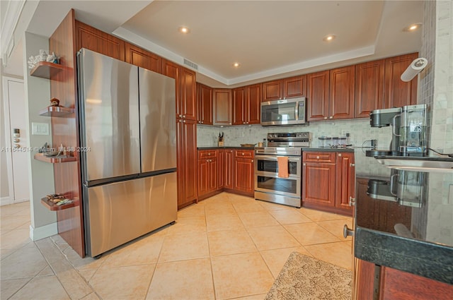 kitchen featuring stainless steel appliances, light tile patterned floors, a raised ceiling, and tasteful backsplash