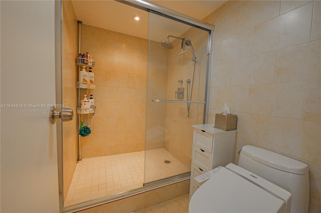 bathroom with toilet, an enclosed shower, tile patterned flooring, and tile walls