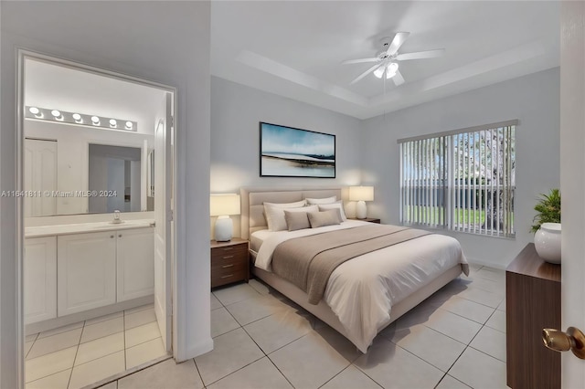 tiled bedroom with ceiling fan, a raised ceiling, sink, and connected bathroom