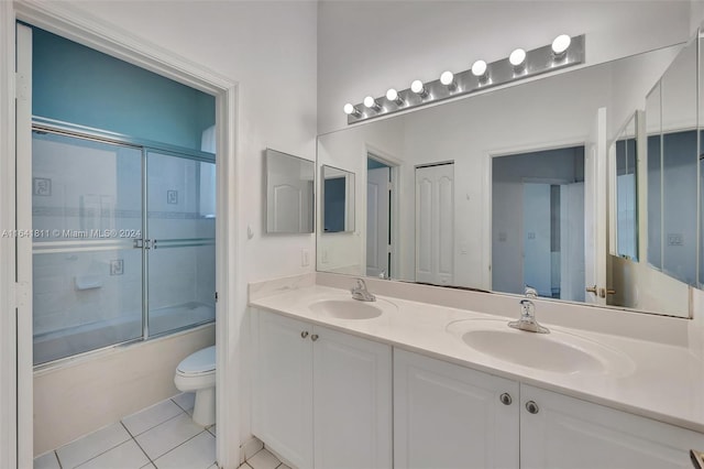 full bathroom featuring tile patterned flooring, toilet, double sink vanity, and enclosed tub / shower combo