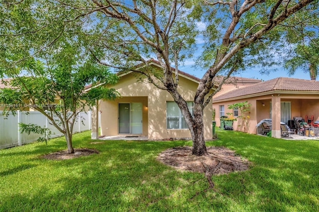 rear view of house with a patio and a lawn