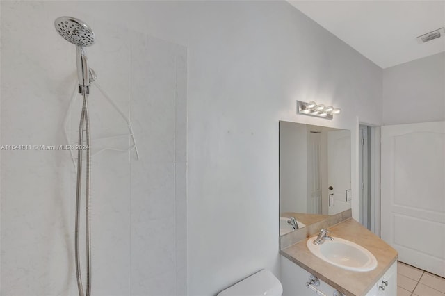 bathroom with tile patterned flooring, toilet, vanity, and tiled shower