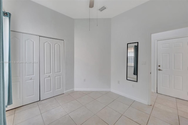 unfurnished bedroom featuring ceiling fan, light tile patterned flooring, and a closet