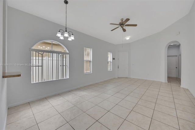 tiled spare room with ceiling fan with notable chandelier