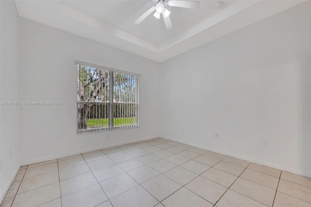 spare room with light tile patterned floors, a raised ceiling, and ceiling fan