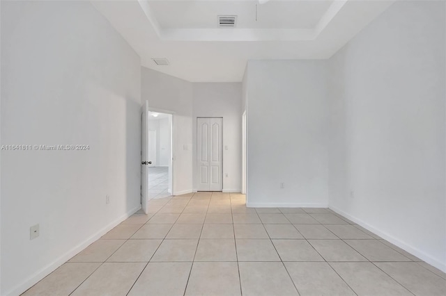 tiled spare room featuring a tray ceiling