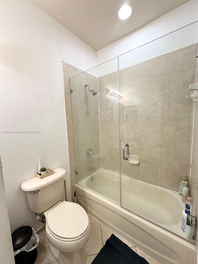 bathroom featuring enclosed tub / shower combo, toilet, and tile patterned floors