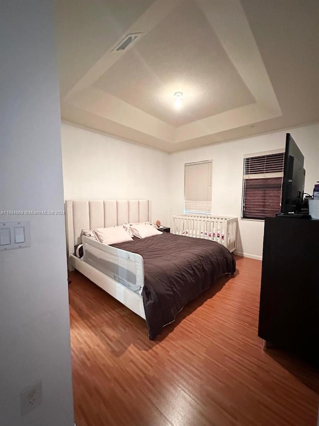 bedroom featuring a raised ceiling and hardwood / wood-style floors