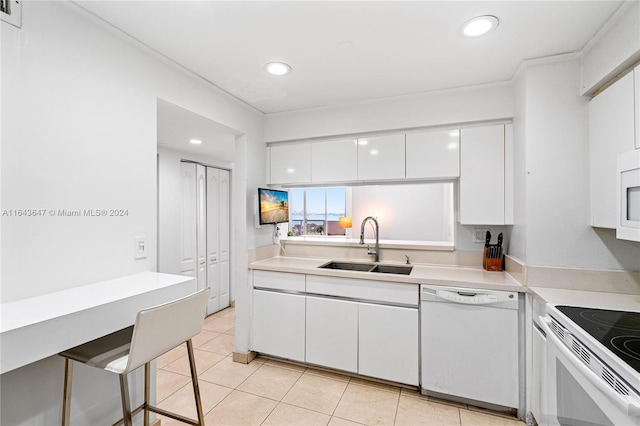 kitchen with light tile patterned floors, white appliances, white cabinetry, sink, and a kitchen breakfast bar