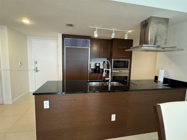 kitchen with dark brown cabinetry, track lighting, light tile patterned floors, island range hood, and black appliances