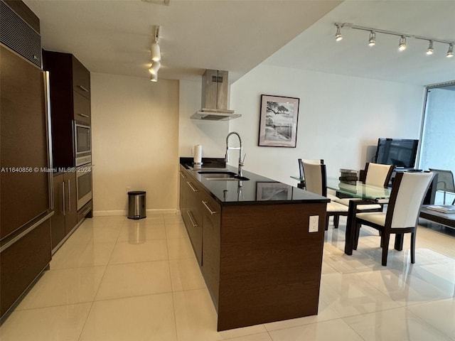 kitchen with sink, wall chimney range hood, light tile patterned floors, track lighting, and built in appliances