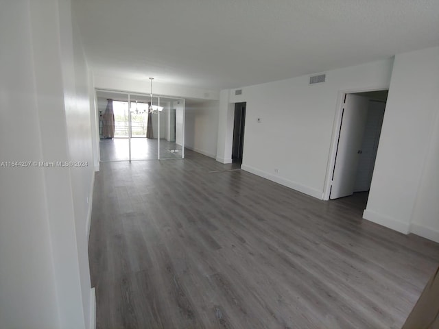 empty room featuring wood-type flooring and a chandelier