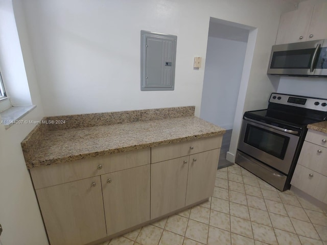 kitchen featuring light brown cabinetry, appliances with stainless steel finishes, light stone counters, and electric panel