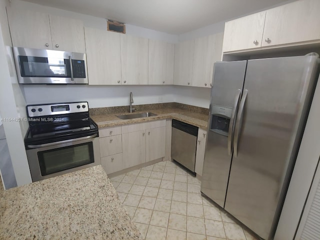 kitchen featuring light brown cabinets, light stone countertops, light tile patterned floors, sink, and stainless steel appliances