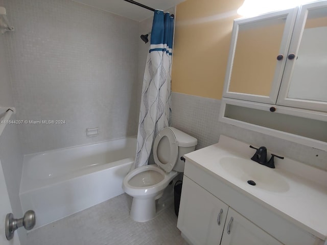 full bathroom with shower / tub combo with curtain, vanity, tile patterned floors, tile walls, and toilet