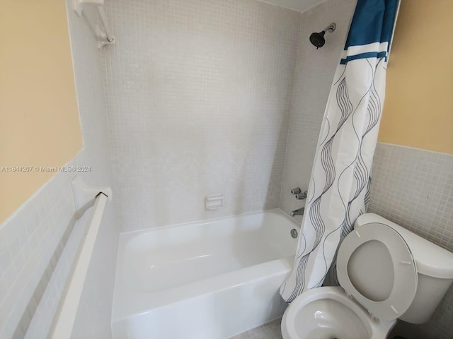 bathroom featuring shower / tub combo, toilet, and tile walls