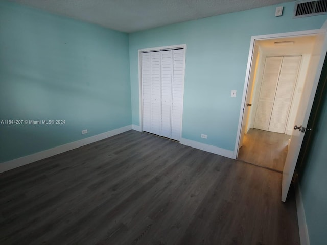 unfurnished bedroom featuring dark hardwood / wood-style flooring, a closet, and a textured ceiling