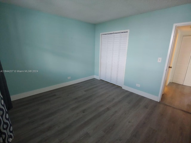 unfurnished bedroom featuring a closet and dark hardwood / wood-style floors