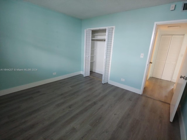 unfurnished bedroom featuring a closet and dark hardwood / wood-style flooring