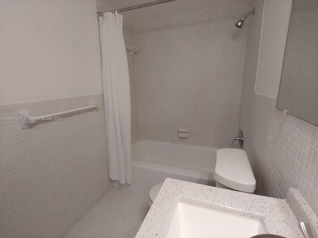 bathroom with tile walls, shower / bath combination with curtain, and toilet