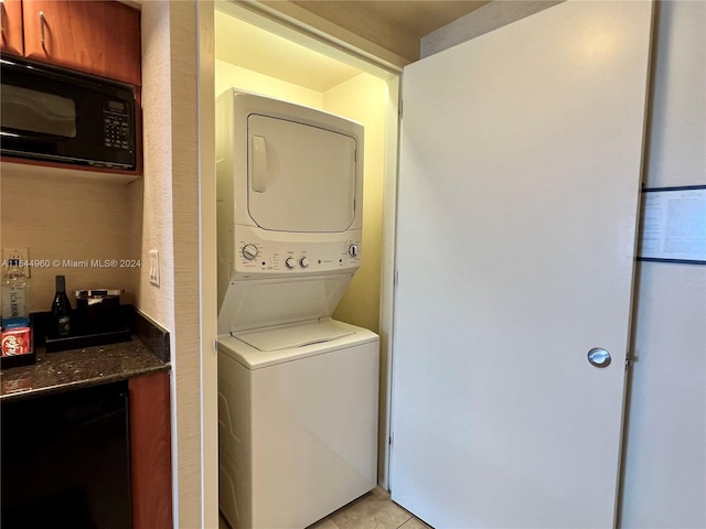 laundry room featuring light tile patterned floors and stacked washer and dryer