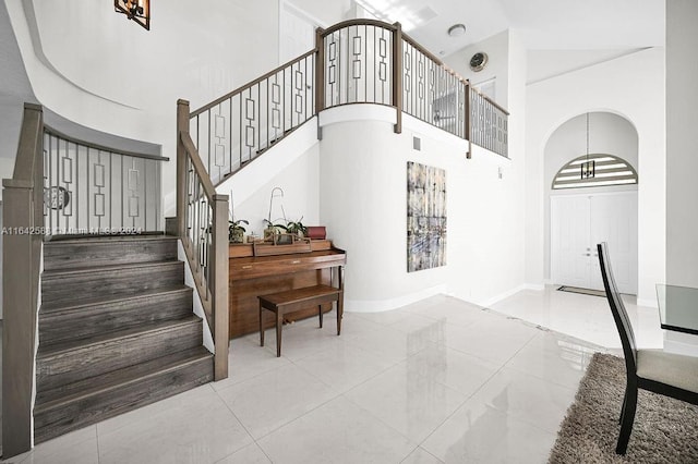 stairs with a towering ceiling and tile patterned floors