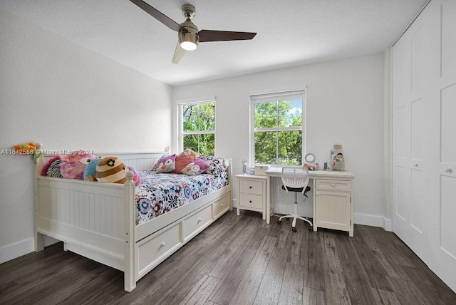 bedroom with dark hardwood / wood-style flooring, ceiling fan, and built in desk