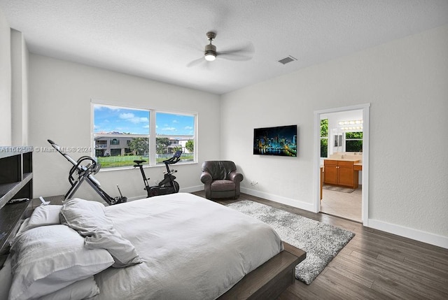 bedroom with ceiling fan, multiple windows, dark hardwood / wood-style floors, and ensuite bath