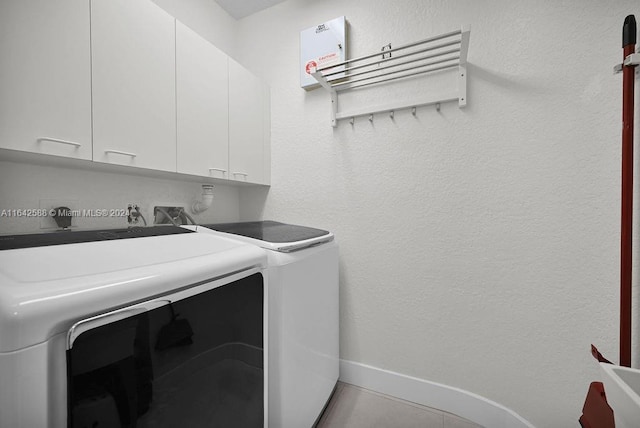 laundry room featuring cabinets, light tile patterned floors, and separate washer and dryer