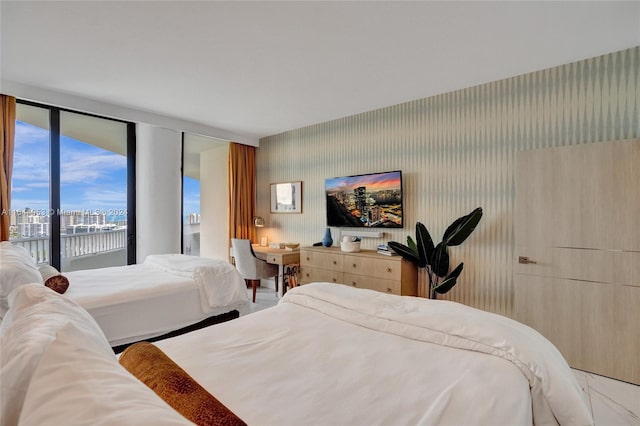 bedroom featuring access to exterior, a city view, a water view, and wallpapered walls