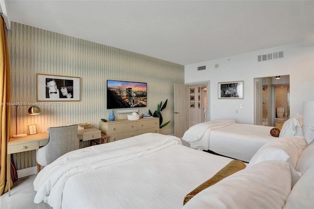 bedroom with baseboards, ensuite bath, visible vents, and wallpapered walls