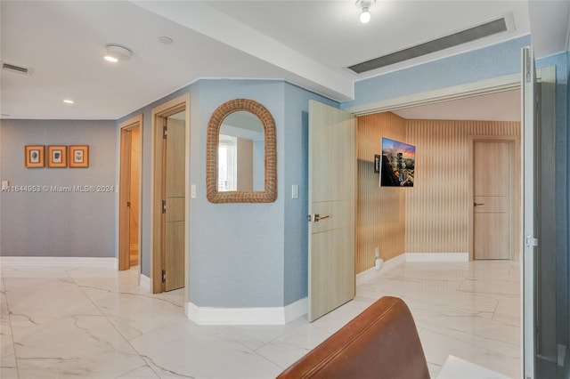 hall featuring marble finish floor, baseboards, and visible vents