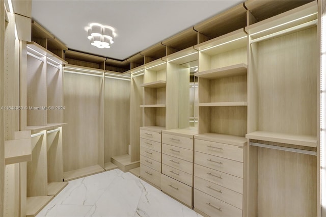 spacious closet with light tile patterned flooring and an inviting chandelier