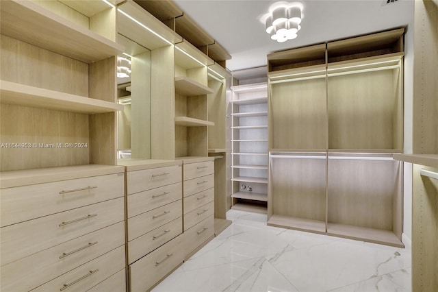 walk in closet with an inviting chandelier and light tile patterned flooring